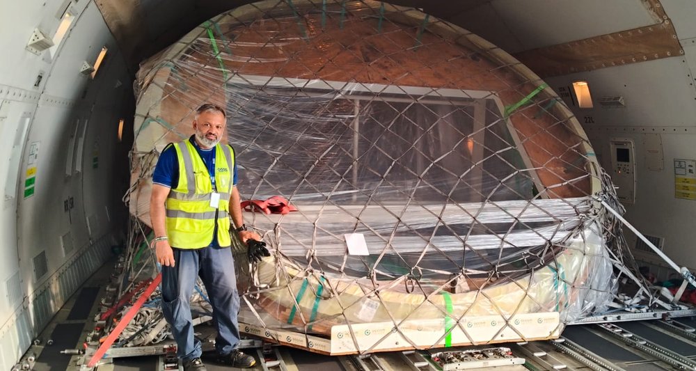 AGOS loadmaster beside a netted satellite ring ULD inside a freighter main deck